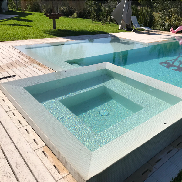 spa cuadrado junto a piscina en tono blanco