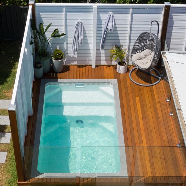 White plunge pool by South Coast Plunge Poolsin a small backyard with wooden decking