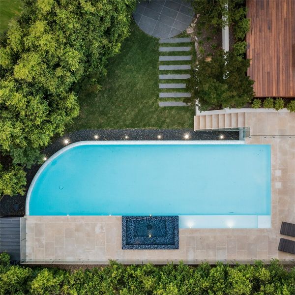 Drone view of an infinity pool with built-in spa in a contrasting color, in a Coolabah Landscape project in which straight lines are combined with a curved end