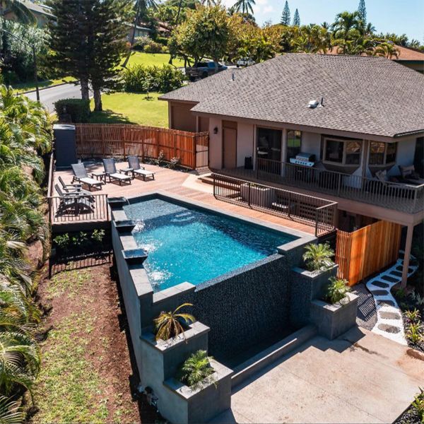 drone view of a custom trapezoidal infinity pool elevated on sloping ground, in a single family home, by Maui Pool Masters