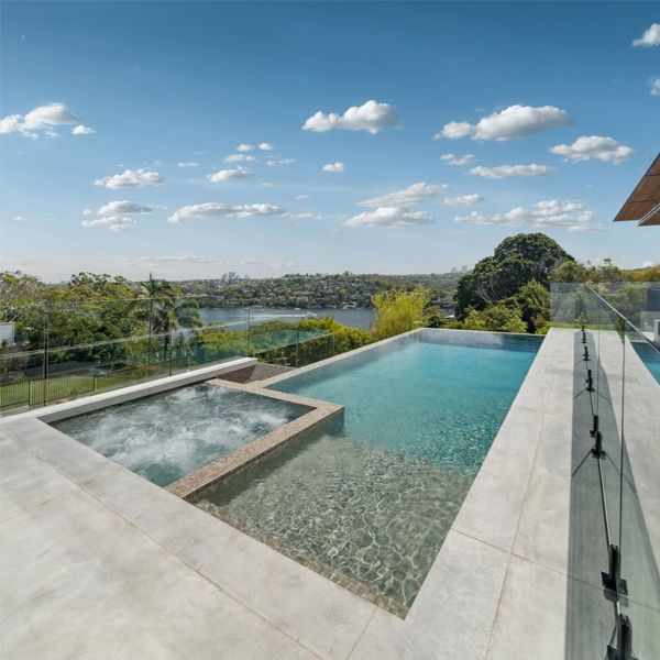 Beautiful infinity pool by FreesStyle Pools, with built-in spa, gray tile coating and a spectacular view of the bay