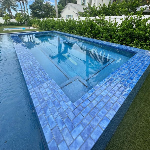 Bright tiled raised overflowing spa in a custom private pool, by Chief Pools Plastering
