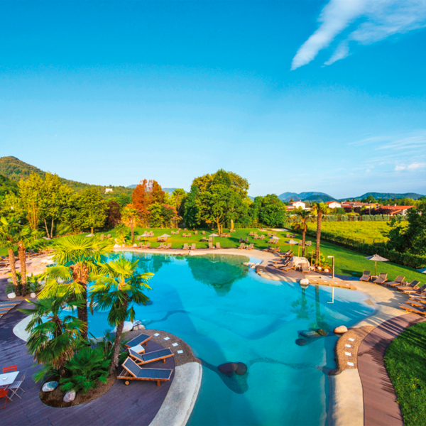 Piscina tipo playa en resort con hamacas alrededor