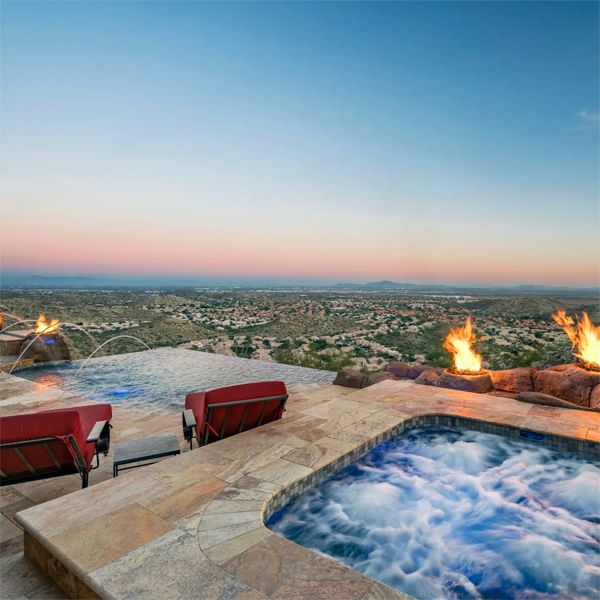 custom infinity pool and spa, by Morris Pools, surrounded by natural stone and water features, at sunset