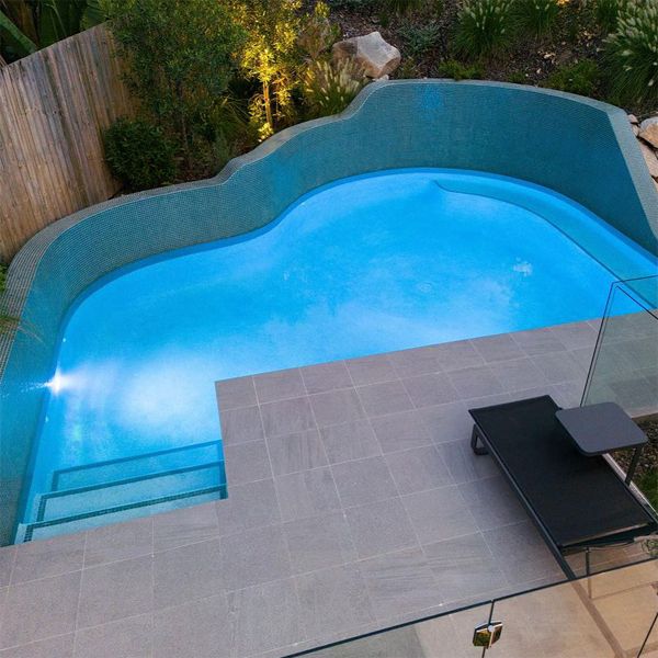 custom pool by Rogers Pools, characterized by its rounded and irregular shapes, and especially by the wall that rises from the very edge of the pool
