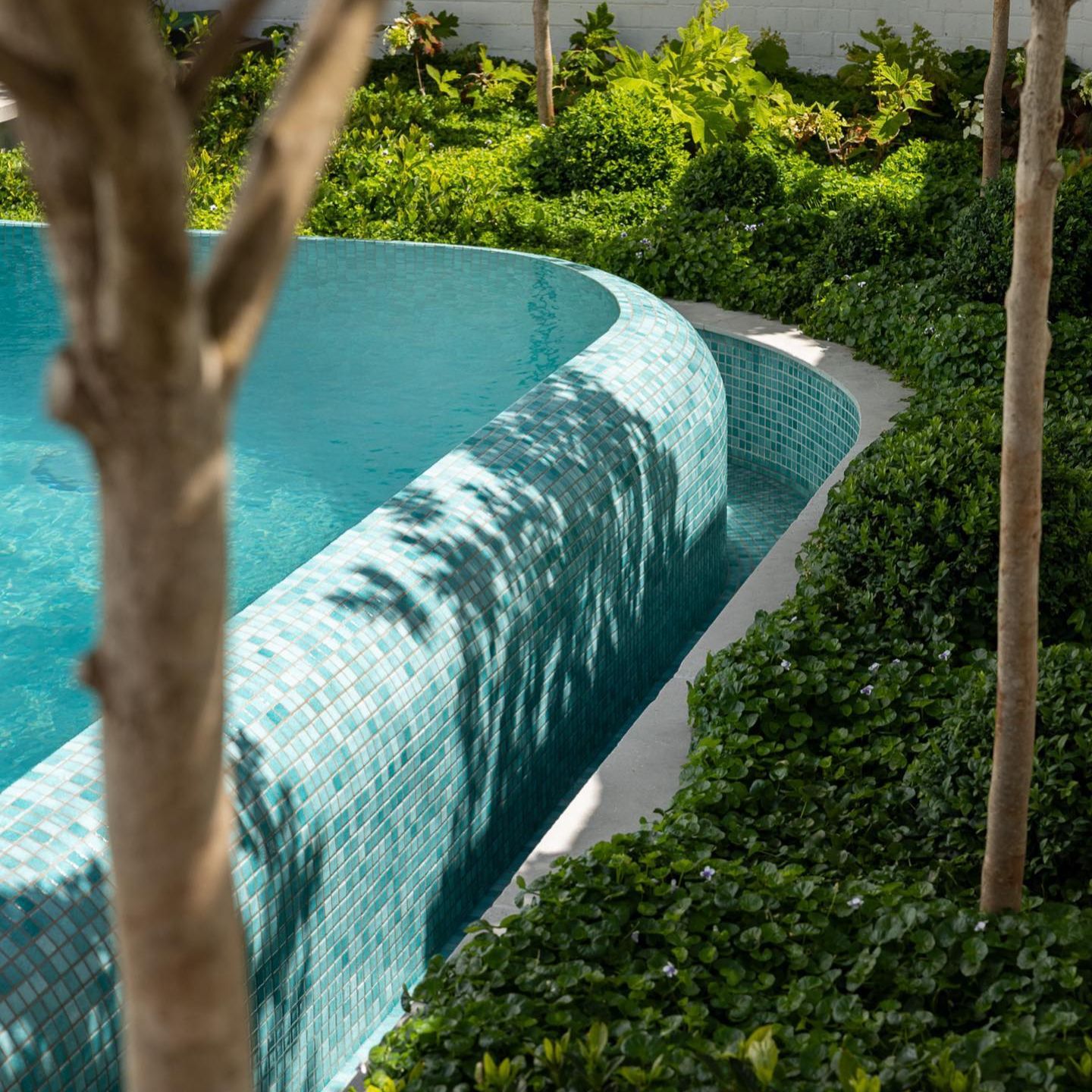 Detail of rounded overflow area and turquoise green tones, in an infinity pool by Grange Pools