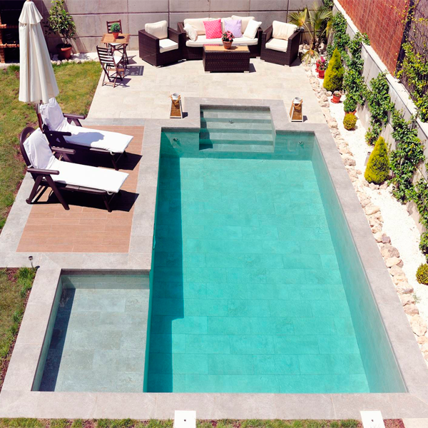Vista aérea de piscina rectangular clásica con espacio playa lateral y revestimiento porcelánico