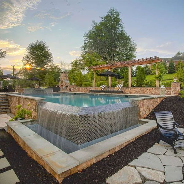 Infinity pool, overflowing in a corner, with overflowing spa, by Rock Water Farm, in an environment where the use of stone stands out