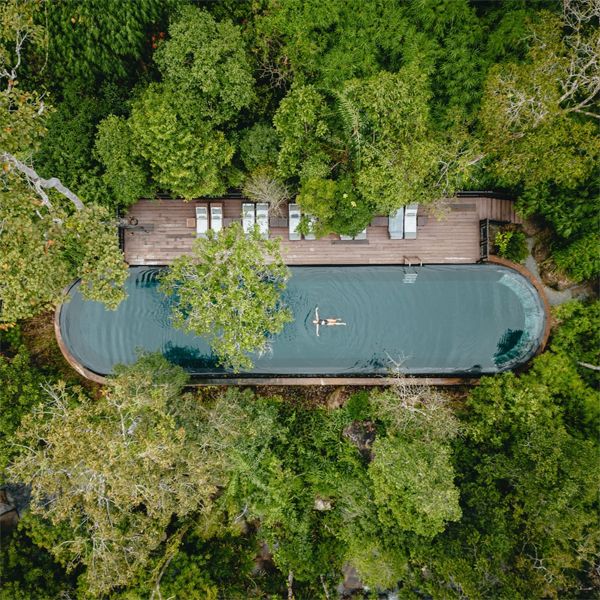 drone view of a stainless steel infinity pool in the middle of the jungle, by Bill Bensley Architects