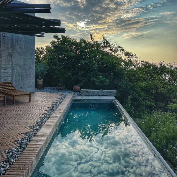 infinity pool at sunset in a rustic design house project, by Espacio 18 Arquitectura