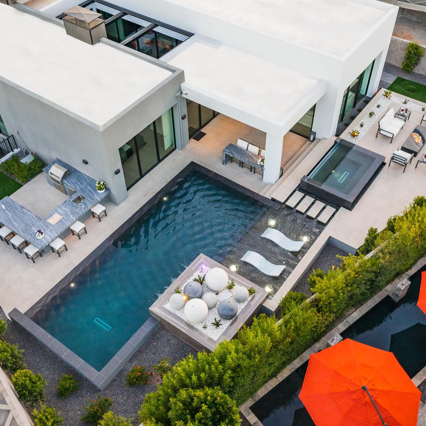 Drone view of a a modern and refined garden, with a geometric infinity pool, overflowing spa, outdoor lounge and relax area, by Lavender Landscape Design
