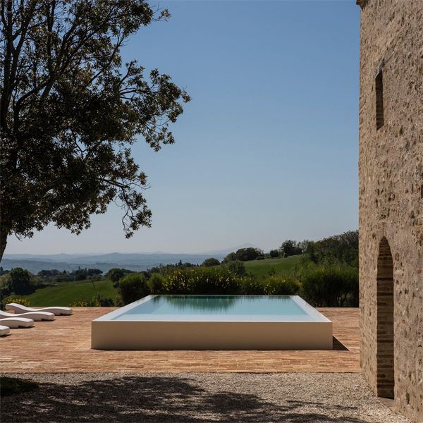 Infinity white pool, with a minimalist design, in a rustic space, in the middle of the countryside, from a project by Wespi Meuron Romeo Architetti