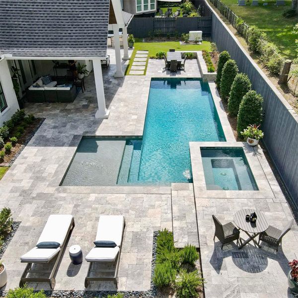 Drone view of a complete landscaping project by Smelek Design with an elegant geometric pool and spa, in a garden with stone floor