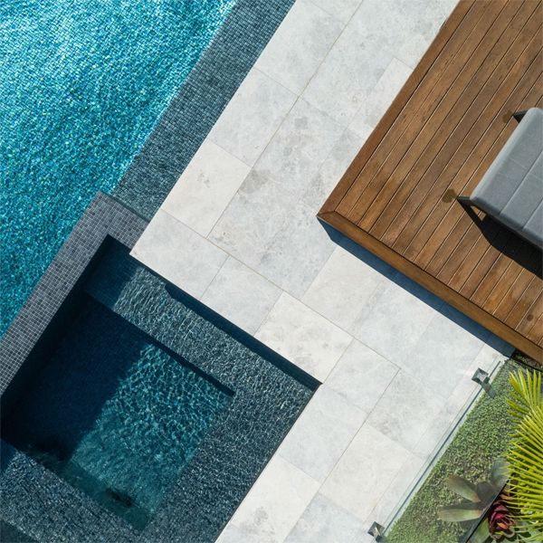 Detail of the interior coating of the pool, in gray glass tile, the paved area, the garden area and wooden terrace, in a project by Splish Splash Pools