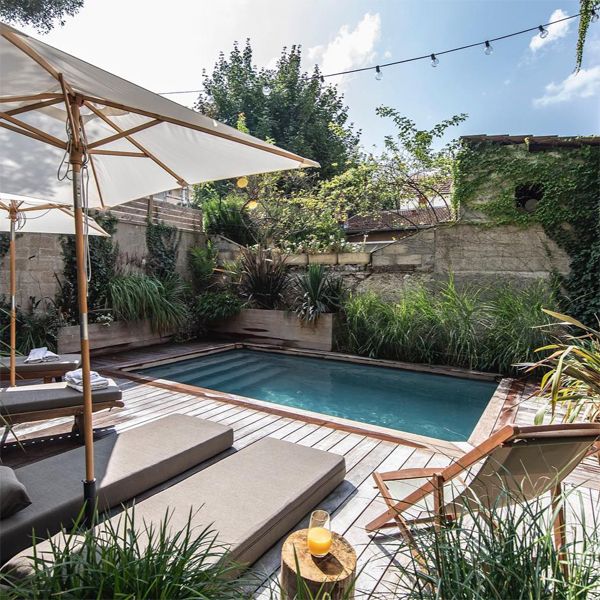 Private mini pool in a classic rectangular design, by Magiline Japan, in a small backyard with wooden decking and different plants, hammocks, umbrellas...