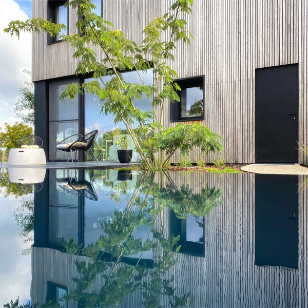 black overflow pool, by Art Pools, reflecting the modern house and outdoor funiture