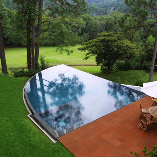 piscina infinity de forma redondeada en medio del bosque