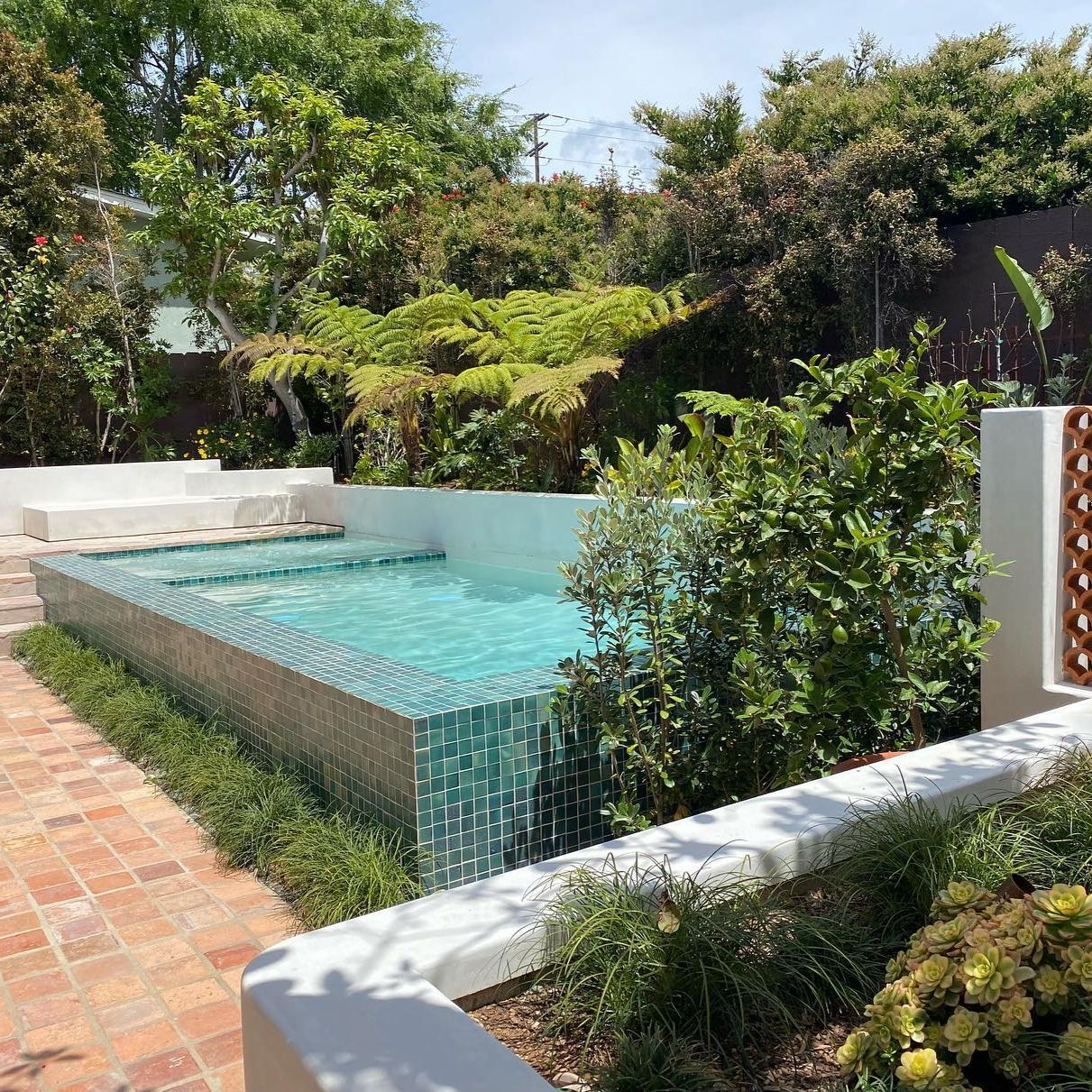 Above ground mini pool with built-in spa and green glass mosaic tile coating, in a landscpaing project by Falling Waters Landscape