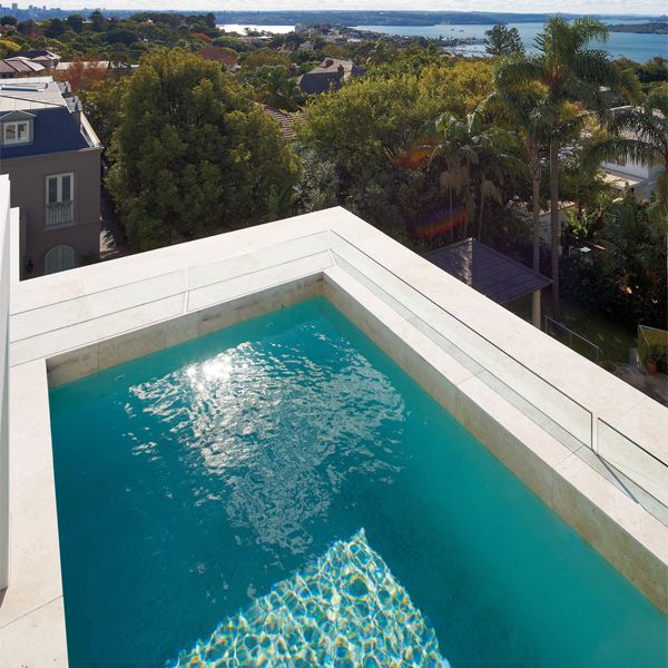 Elegant pool on the rooftop of a private house, by Artesian Pools, with interior coating in New Zealand white pebble and exterior in travertine