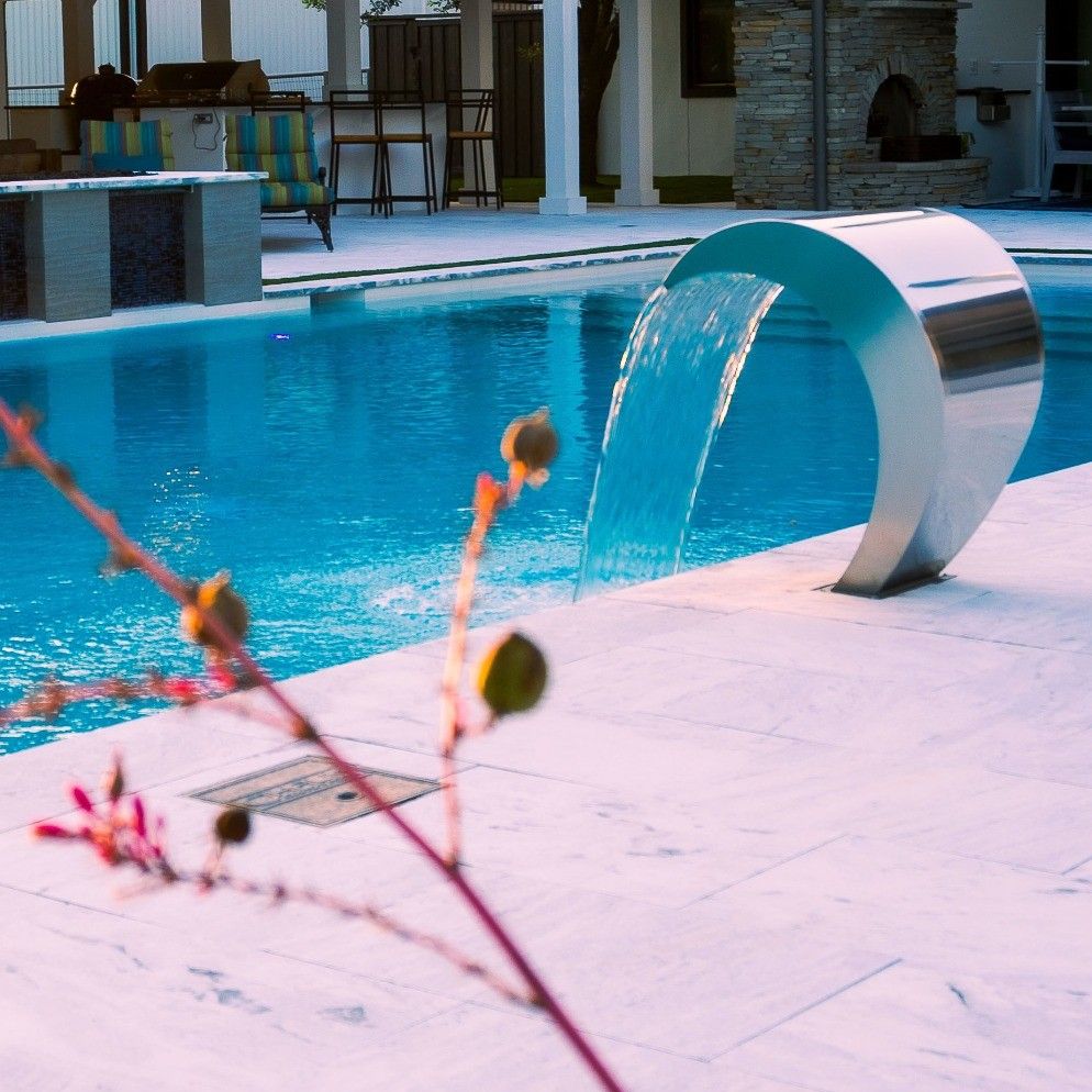 Stainless steel waterfall on the edge of a luxury infinity pool, by Hauk Custom Pools