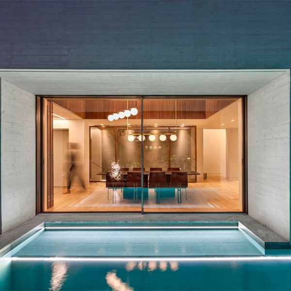 sitting room view from a minimalist modern pool at night, in a project by Divercity Architects