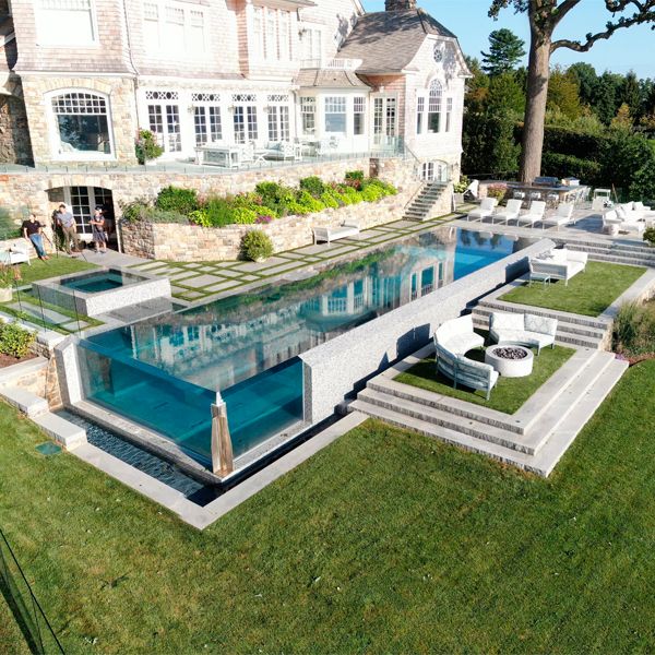 drone view of a luxury lap infinity pool with transparent walls, by Drakeley Pool Company, in a house with a design that combines modern and classic
