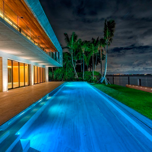 transparent infinity lap pool at night by Regency Pool and Spa