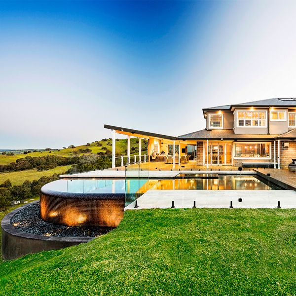 Custom infinity pool with built-in spa, by Esjay Landscapes, lighted at sunset