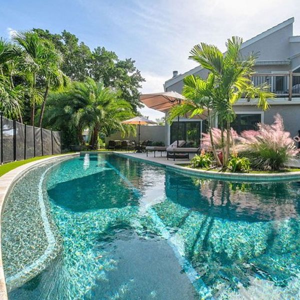 Custom curved L-shaped lap pool with a coating that gives the water a gorgeous turquoise color, by Almar Jackson