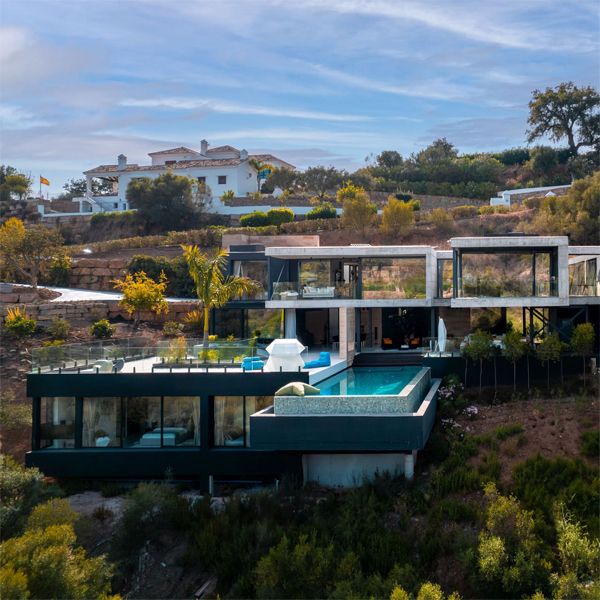Drone view of a luxury infinity pool in a modern house by Flow81, based on different cubic spaces that seem to float on a hill