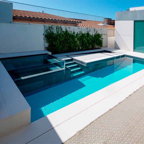 A unique custom built moving floor pool with see-through spa by Mission Pools in a small backyard of a single-family home