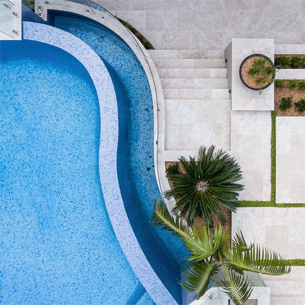 Drone view of a custom curved design infinity pool in a modern backyard, by Fluid Design