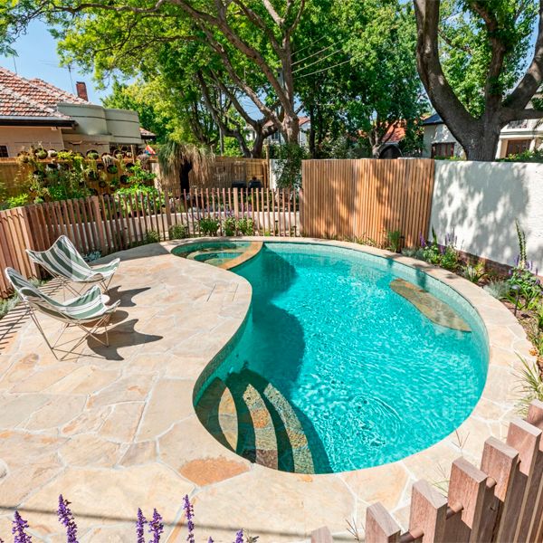 Kidney-shaped private pool, with a built-in spa, and a coating that combines glass tile mosaic and stone, by Striking Pools