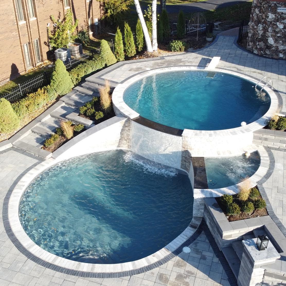 Drone view of a two-level pool built by Coastal Pools in which a circular design pool overflows over another circular one