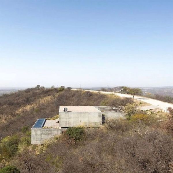 drone view of a modern and minimalist concrete house, with an infinity pool, by Gaston Sironi Arquitectos, located on a hill