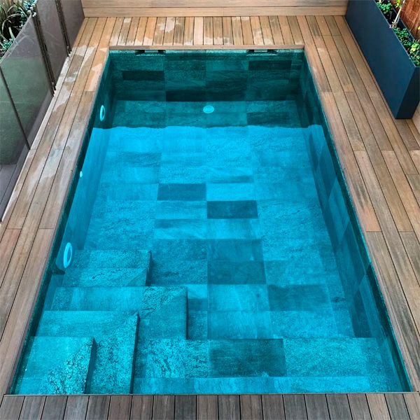 drone view of a private pool with a classic design and porcelain stoneware cladding, surrounded by synthetic wood decking, in a project by Piscinas Los Hermanos