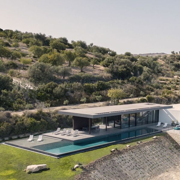 Drone view of a modern and minimalist house project by GnB Studio, with spectacular L-shaped infinity pool, ideal for swimming, located on a small hill