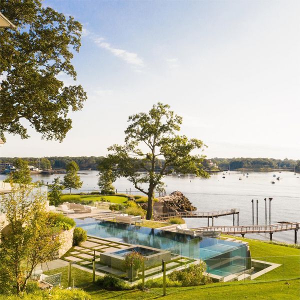 drone view of a luxury lap infinity pool with transparent walls, by Drakeley Pool Company, in a house with a design that combines modern and classic, near to the lake