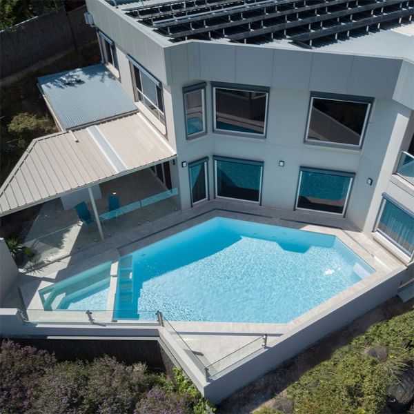 drone view of a custom pool and spa, with a bright white glass mosaic coating, by Adelaide Classic Pools