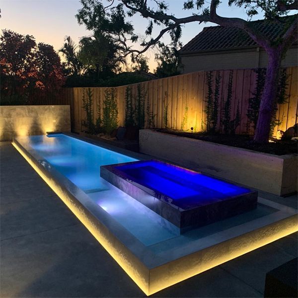 minimalist pool and spa, lighted at night, by Graziani Pools, in a modern garden