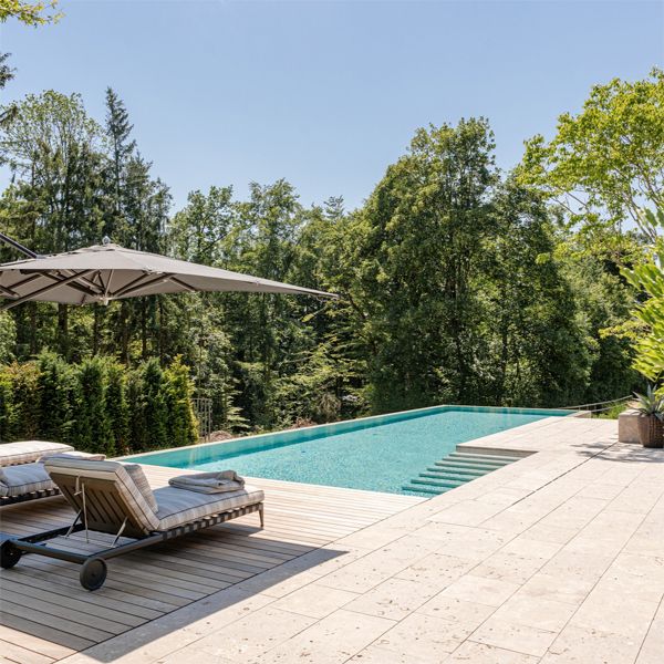 custom infinity pool by Vivell Schwimmbadtechnik, in a terrace with pavement and wooden decking