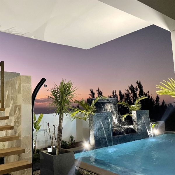 Private mini pool with a Zen design and natural stone coating, by Sarana Pools, decorated with waterfalls and a figure of Buddha, at night