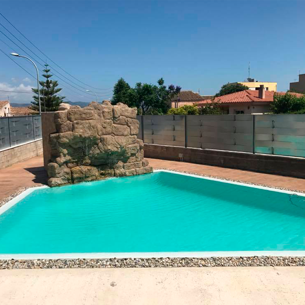 piscina desbordante de formas geométricas y decoración de piedras alrededor y cascada en imitación de piedra