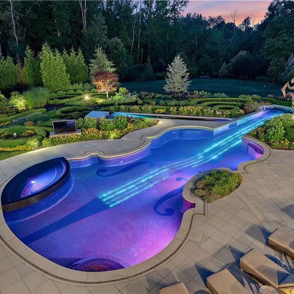 a unique pool and spa with a violin desin, at night, by Cipriano Landscape Design