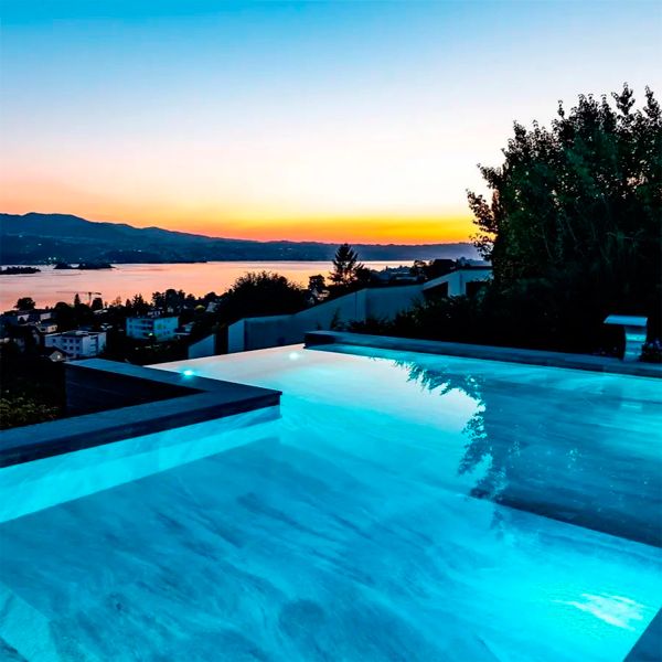 Elegant bespoke luxury infinity pool with stainless steel waterfall and spectacular views over the lake, by Vita Bad, sunset view