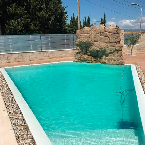piscina desbordante de formas geométricas y decoración de piedras alrededor y cascada en imitación de piedra