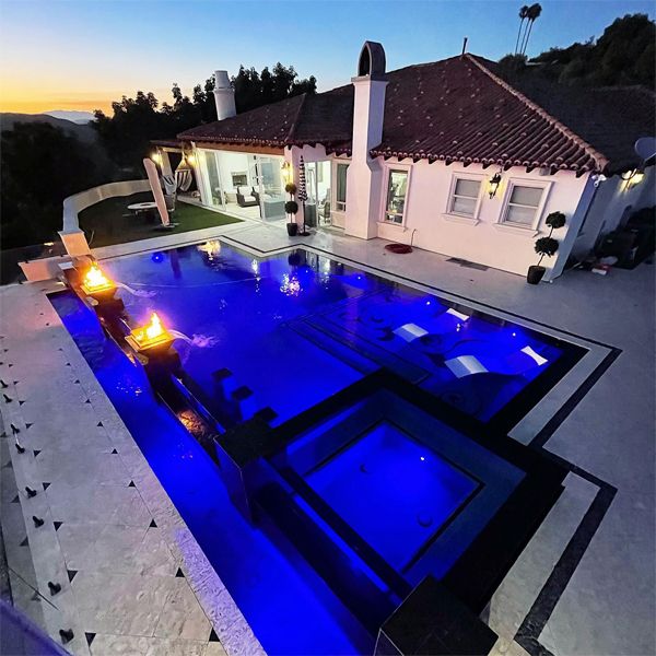 unique infinity pool with transparent wall, built-in spa and exclusive design coating, by Element Pools and Spas, at night