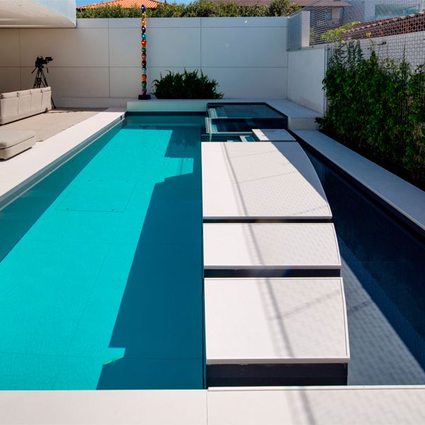 A unique custom built moving floor pool with transparent spa by Mission Pools in a small backyard of a single-family home