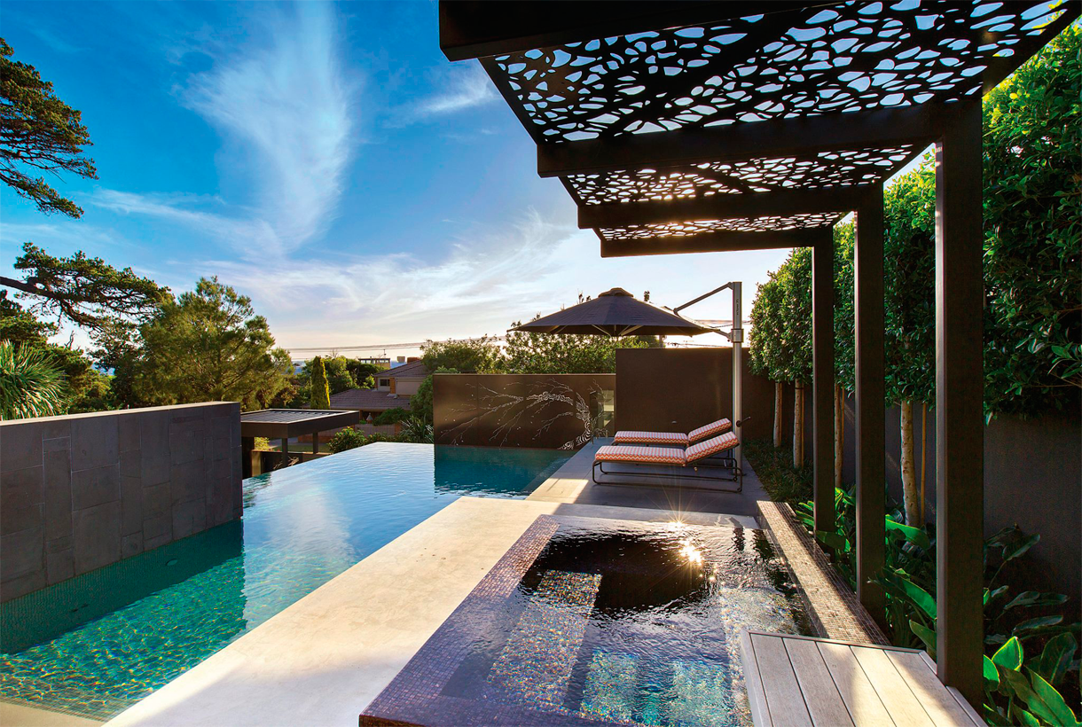 Infinity pool in contrast to its surroundings; pergola, pavement, stone wall, plants, spa …