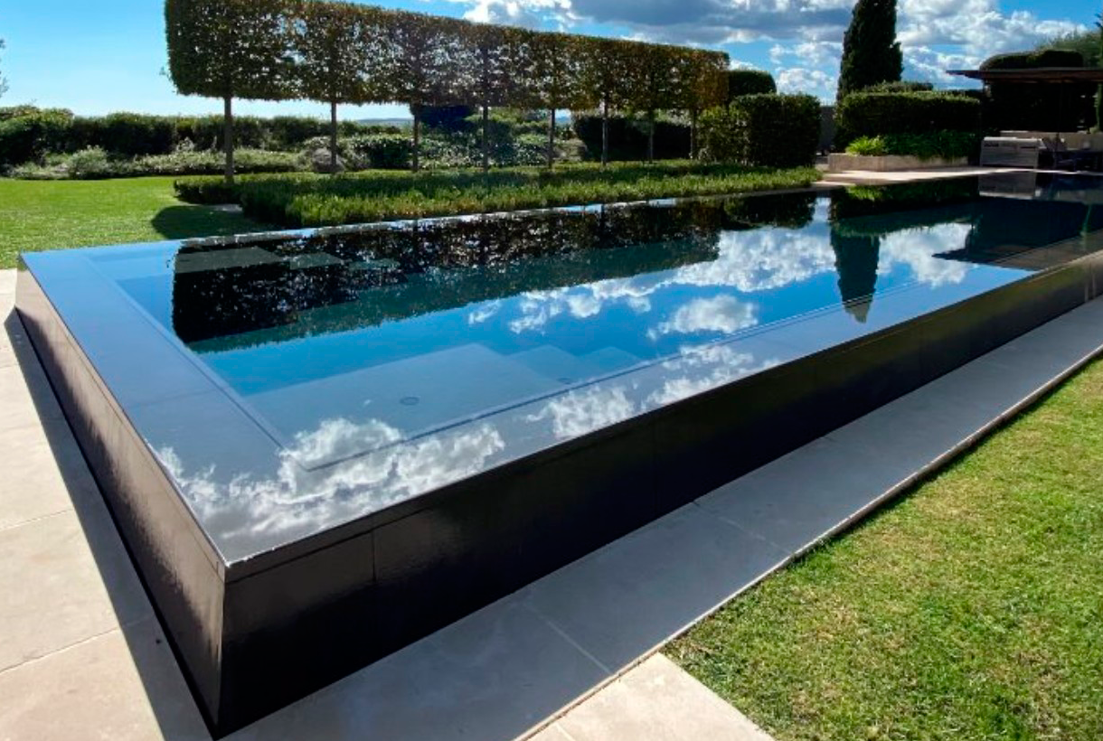 Overflowing pool of mirror type in dark color, semi-elevated above the ground